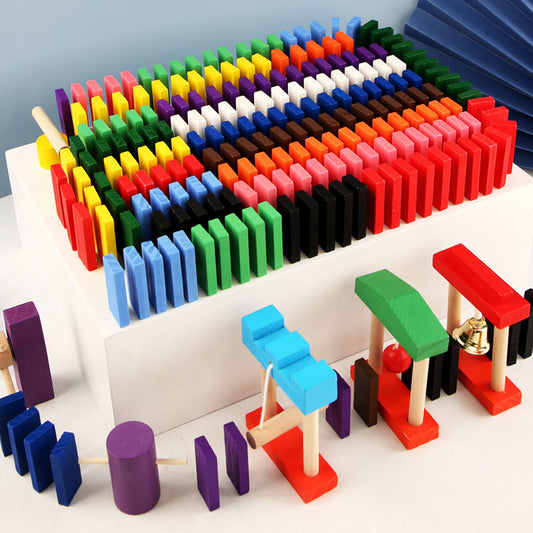 The image showcases a colorful array of wooden domino blocks arranged in neat rows on a white platform. The dominoes come in various vibrant colors, including red, yellow, green, blue, purple, black, and white. Additionally, there are small structures built with the dominoes and other wooden pieces, adding an element of creativity and construction to the play. This setup is visually appealing and highlights the potential for imaginative and educational play with the domino blocks.