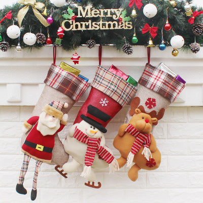 Christmas sock gift bag ornaments filled with small presents, hanging on a decorated Christmas tree