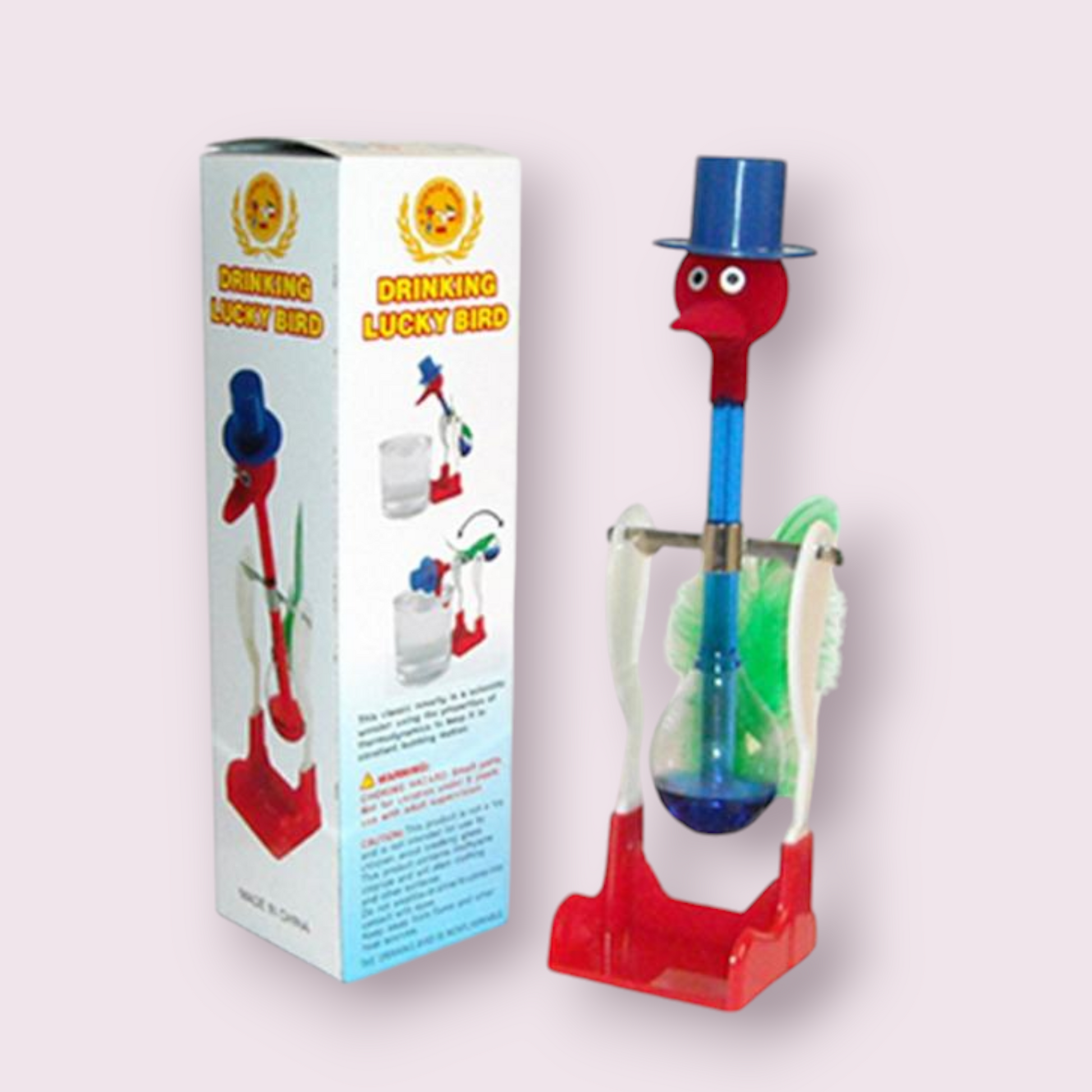 Original Drinking Bird toy featuring a red and white color scheme with a blue top hat. The bird has a clear glass tube body filled with a red liquid, which dips into the beak when activated. The base and head of the bird are red, while the midsection is white, creating a striking contrast. This classic novelty item is both amusing and fascinating to observe as it perpetually ‘drinks’ from a cup when set up properly.